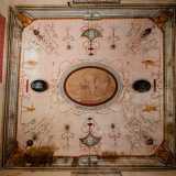 ...da un soffitto con volta a crociera decorato con greche, statuette dipinte, bucrani e volti